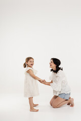 mother in summer clothes has fun with cute little girl. Mother and little daughter isolated on white background. Mother's day, love, family, parenthood, childhood concept.