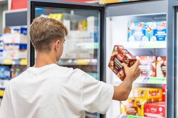 Man choosing frozen food from a supermarket freezer . ice cream,