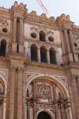 an urban landscape dominated by a large historic building with a dome and bell tower, surrounded by modern residential and commercial buildings. Mountains are visible in the distance, and two construc