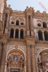 an urban landscape dominated by a large historic building with a dome and bell tower, surrounded by modern residential and commercial buildings. Mountains are visible in the distance, and two construc