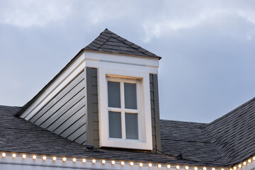 A house with a window on the roof. garret house with roof shingle.