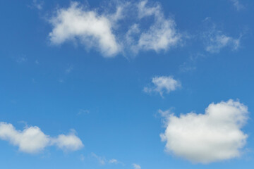 White fluffy clouds in the sky. Blue sky and cloud cover on a sunny summer day. Empty background, copy space