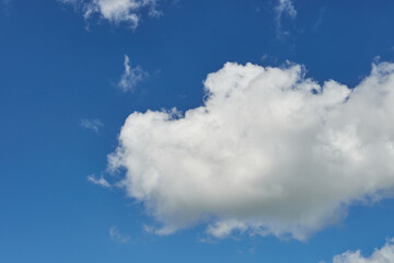 White fluffy clouds in the sky. Blue sky and cloud cover on a sunny summer day. Empty background, copy space