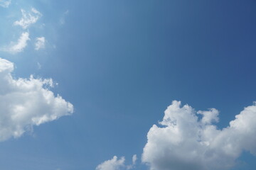 White fluffy clouds in the sky. Blue sky and cloud cover on a sunny summer day. Empty background, copy space