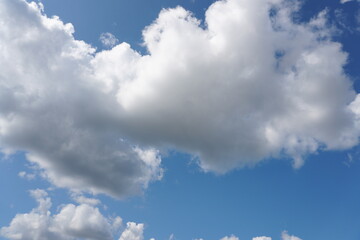 White fluffy clouds in the sky. Blue sky and cloud cover on a sunny summer day. Empty background, copy space
