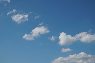 White fluffy clouds in the sky. Blue sky and cloud cover on a sunny summer day. Empty background, copy space