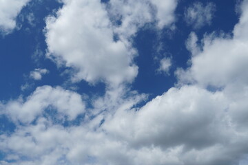 White fluffy clouds in the sky. Blue sky and cloud cover on a sunny summer day. Empty background, copy space