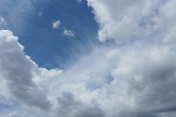 White fluffy clouds in the sky. Blue sky and cloud cover on a sunny summer day. Empty background, copy space