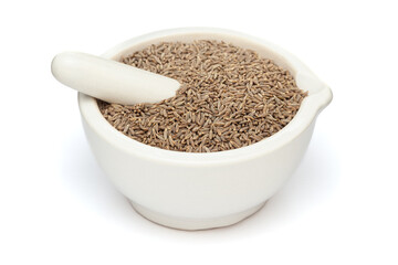 Close-up of Dry Organic Cumin Seeds (Cuminum cyminum) or jeera, in white ceramic mortar and pestle, isolated on a white background.