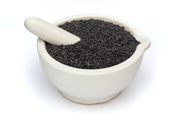 Close-up of Dry Organic Black Sesame (Sesamum indicum) Seeds, in white ceramic mortar and pestle, isolated on a white background.