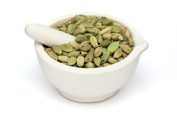 Close-up of Dry Organic Cardamom or cardamum (Elettaria cardamomum), in white ceramic mortar and pestle, isolated on a white background.