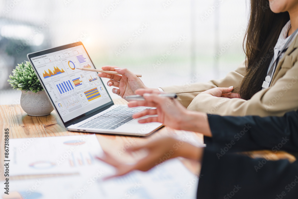 Wall mural two professional analyzing financial data graphs, charts on laptop display at a modern workspace. fi