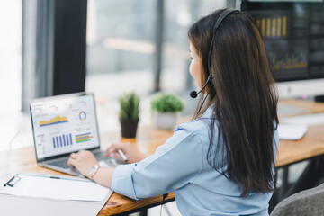 Operator wearing a headset, using a dashboard on laptop for data analysis in modern office. Selective focus