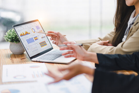 Two professional analyzing financial data graphs, charts on laptop display at a modern workspace. Financial analysis or business evaluation concept - Powered by Adobe