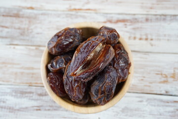 Sweet dates fruit heap in the bowl. Dried date palm fruits or kurma, ramadan food