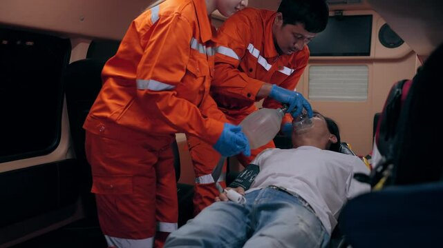 Asian woman and man emergency medical technician (EMT) or paramedic nurse is performing CPR on a patient in an ambulance car