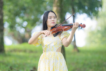 
A young Chinese-Malaysian woman in her twenties, wearing a yellow dress, elegantly plays the...