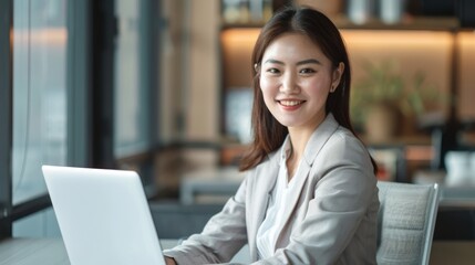 Fototapeta premium a young smiling chinese businesswoman is sitting at his laptop in the office