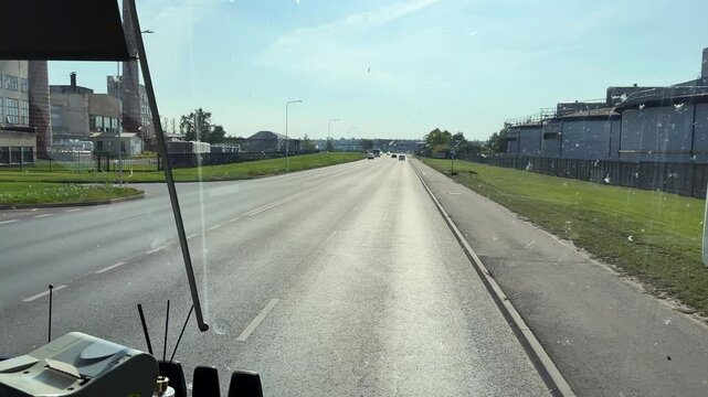 Bus windscreen splattered with insects bugs during long intercity service drive, coach windshield view driving in industrial area of Panevezys city.