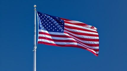 Fototapeta premium A dramatic angle of the American flag, its colors standing out in stark contrast to the deep blue sky behind it, emphasizing its significance.
