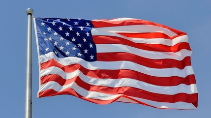 A dynamic capture of the American flag in mid-wave, its colors vibrant and bold against a clear blue sky.