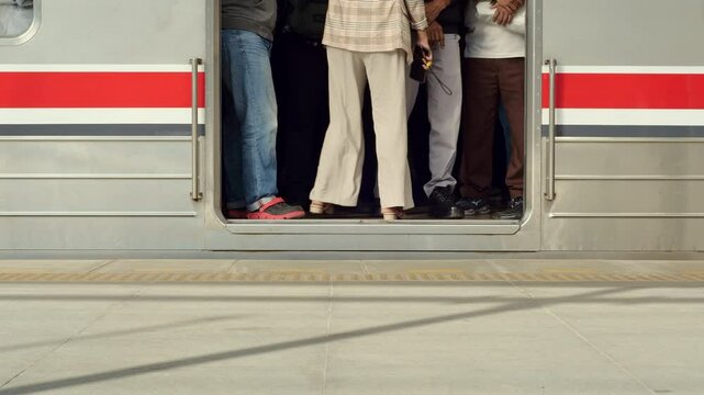 A train car that was very full with the feet of many passengers seemed to be crowded during rush hour, the carriage opened its doors and new passengers boarded