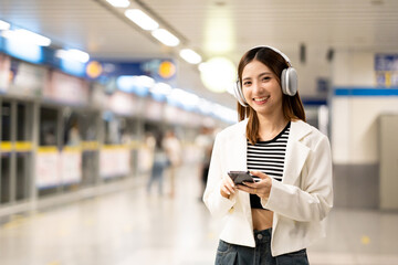 Young asian woman using smartphone application navigate location destination while travel by subway. Asian female with headphone listen to the music by cell phone while traveling in train transport