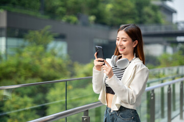 Young asian woman using smartphone while walking in the urban city. Happy Beautiful asian female...