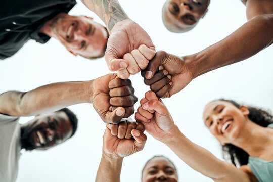 Sky, fist bump and fitness people in outdoor for teamwork, support or running motivation. Low angle, diversity and group of friends with smile for synergy, community or race in morning in Spain