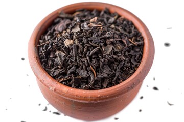 A simple still life scene of a brown bowl filled with black tea leaves, perfect for use in editorial or commercial content related to food, beverage, or lifestyle