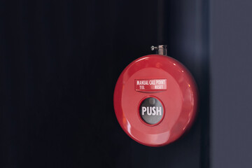 Manual emergency notification tool for fire alarm system, red, mounted on a black-gray background...