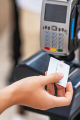 Close-up of a customer's hand using a credit card to pay a cashier at the checkout counter in a supermarket, cashless money and credit card payment technology concept.