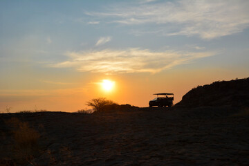 Fototapeta premium Silhouette of a jeep all-terrain vehicle against the background of the evening sky in a desert area. Tourism and summer vacation