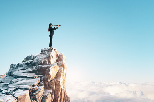 A person standing on a high cliff peak using binoculars, with a clear blue sky and cloud background, concept of vision and exploration. Generative AI