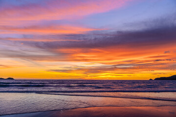 Silhouette of parasailing and people on the beach with the Most beautiful and colourful sunset on Patong Beach Phuket Island Thailand