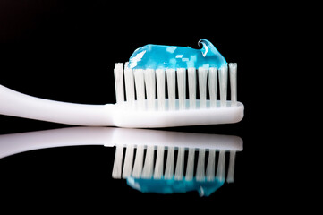 toothbrush and gel paste on black reflective background with copy space