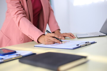 Image of a young Asian female company employee smiling and holding a digital tablet standing on a white background.