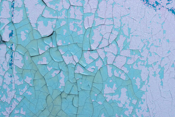 Peeling paint on the wall. Old concrete wall with cracked flaking paint. Weathered rough painted surface with patterns of cracks and peeling. Grunge texture for background and design. High resolution.