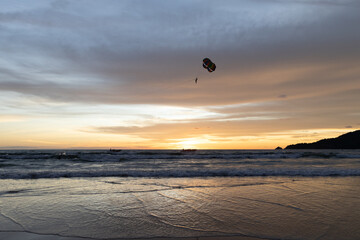 Silhouette of parasailing and people on the beach with the Most beautiful and colourful sunset on Patong Beach Phuket Island Thailand