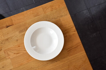 Ceramic white flat plate for food on wooden table top view