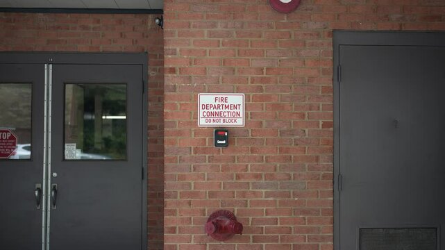 Public school Fire Department Connection sign showing bell and the actual connection for a fire hose.