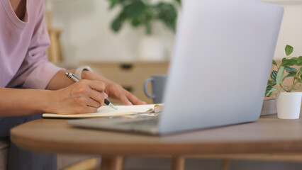 Female entrepreneur working at home to thinking about new startup project and writing note in paper