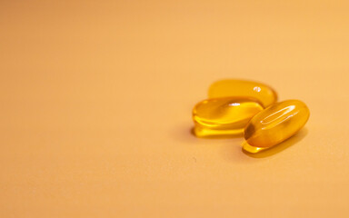 Horizontal close-up of soft capsules of vitamins on amber background.