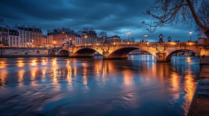 Obraz premium Nighttime Cityscape with Bridge and Reflective River