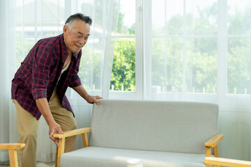 Asian mature man arrange sofa to decoration the living room