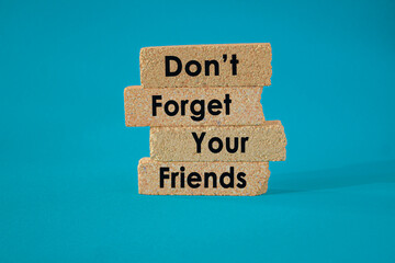 Remembering friends and friendship concept. Concept words Don't Forget Your Friends on brick blocks. Beautiful blue background