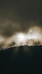 Fototapeta premium A crucifix stands atop a mountain as sunlight breaks through the clouds, creating an inspirational Christian scene. The image symbolizes faith, hope, and divine light