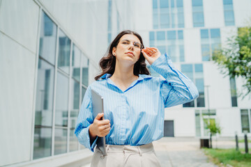 One beautiful young successful business woman going to work at business office modern building while holding laptop and waring glasses