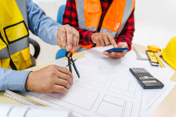 Two men, including a male Asian construction contractor engineer, discuss structural plans and...