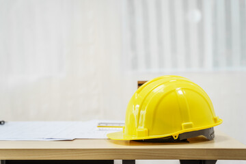 An architect's desk with blueprints and a white hardhat sits empty, ready for the next project. No people are present, highlighting the tools of the trade.